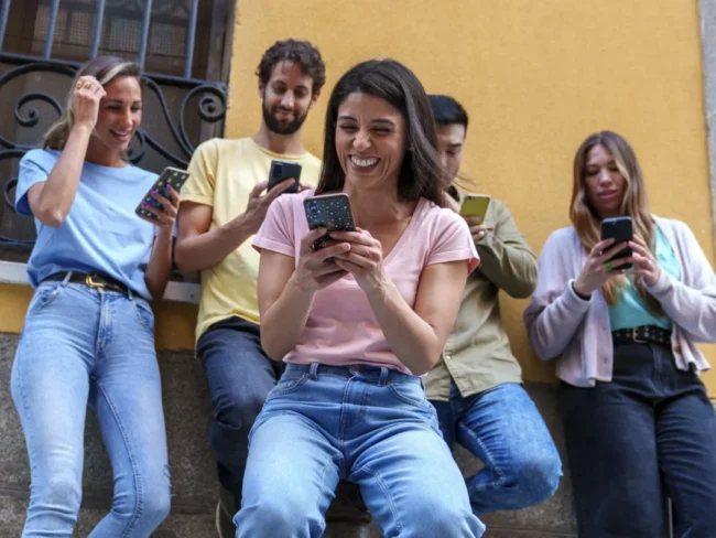 Grupo de personas usando una app móvil para mandar dinero desde USA en su día a día